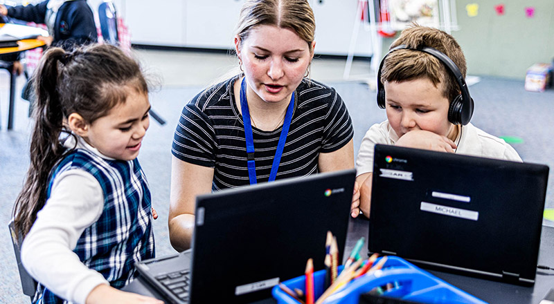 Teacher assisting students at Holy Family Catholic Primary Emerton