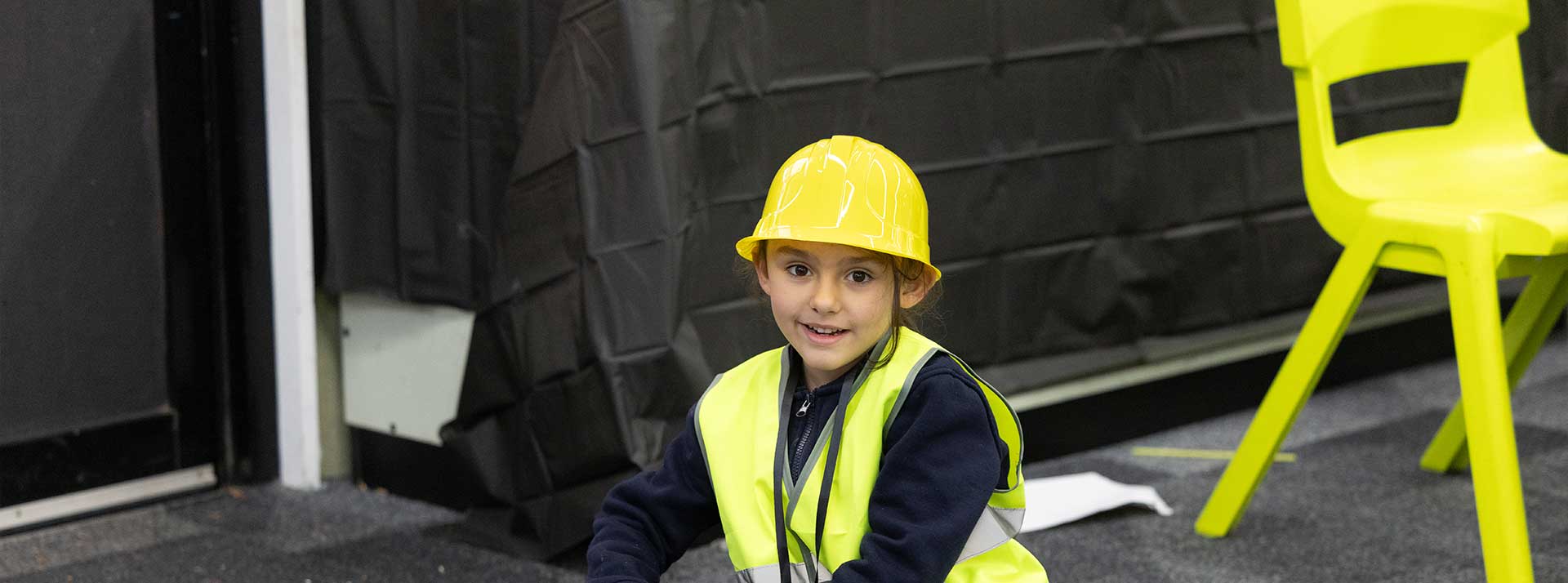 Holy Family Primary Emerton student wearing hard hat. She is constructing a model nuculear power plant.