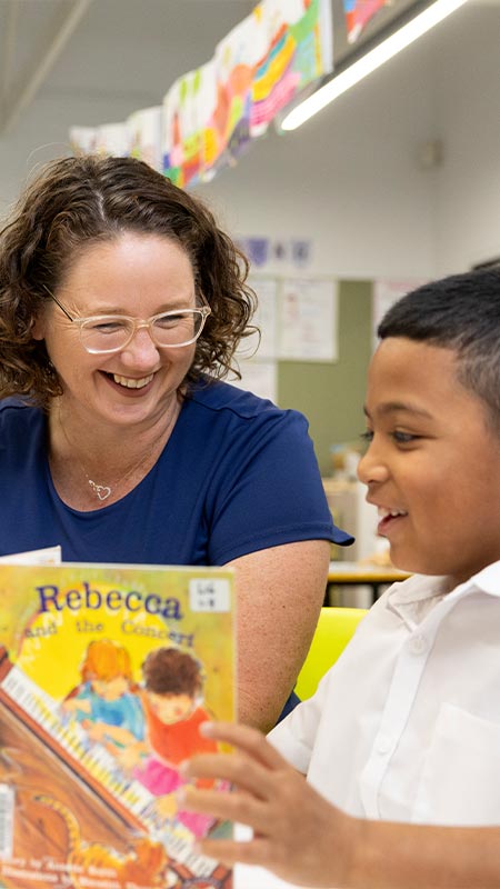 Margaret Rowan, Principal of Holy Family Emerton reading to happy student in class