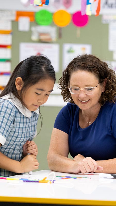 Margaret Rowan, Principal of Holy Family Emerton assisitng happy student in class