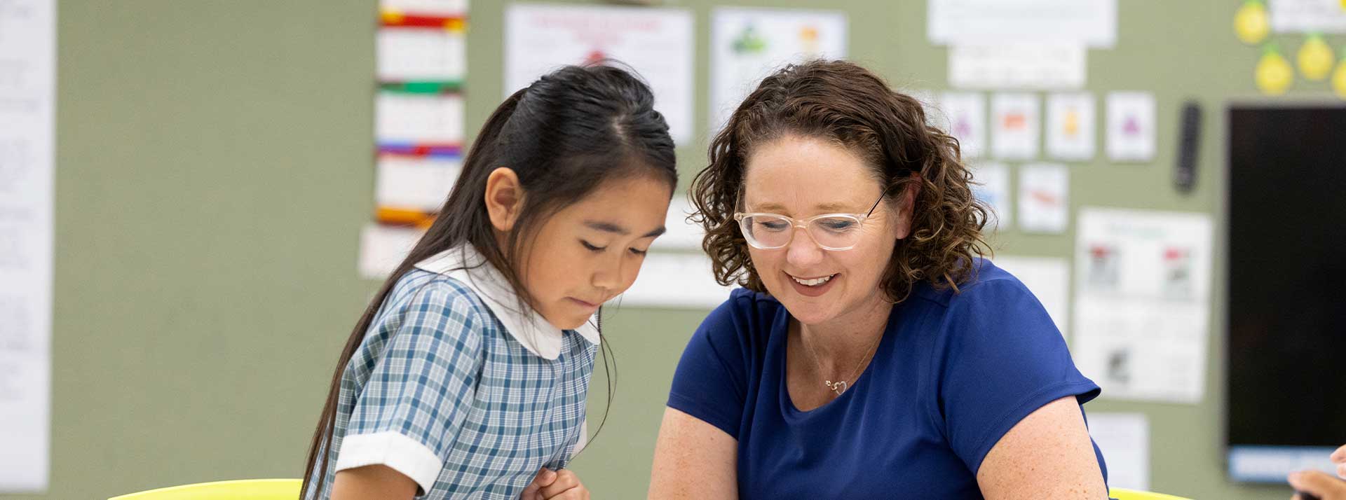 Margaret Rowan, Principal of Holy Family Emerton assisitng happy student in class