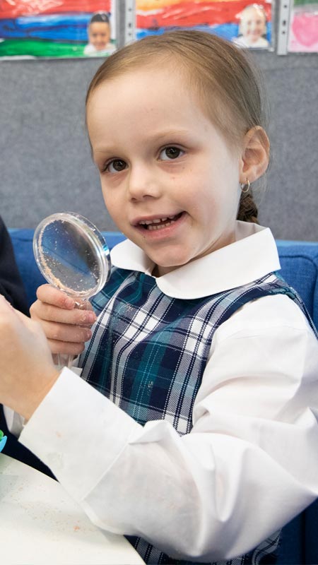 Holy Family Primary Emerton students using magnifying glass in class