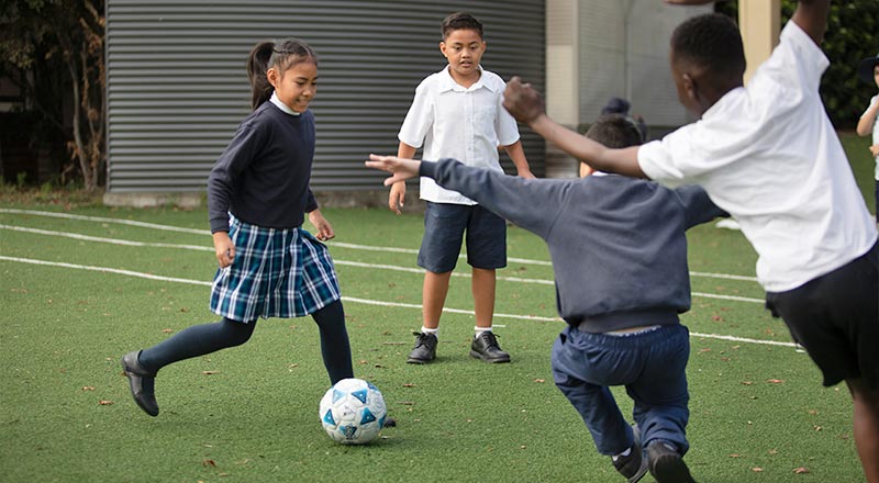 Holy Family Primary students playing soccer in school field