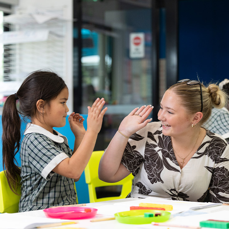 Teacher high fiving Holy Family Primary Emerton student