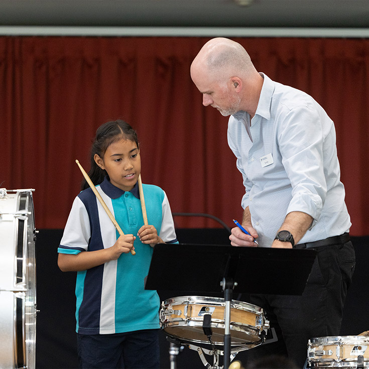 Music teacher assisting student at Holy Family Catholic Primary, Emerton